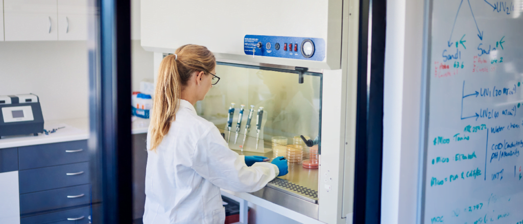 Scientist sitting at safety cabinet examining samples