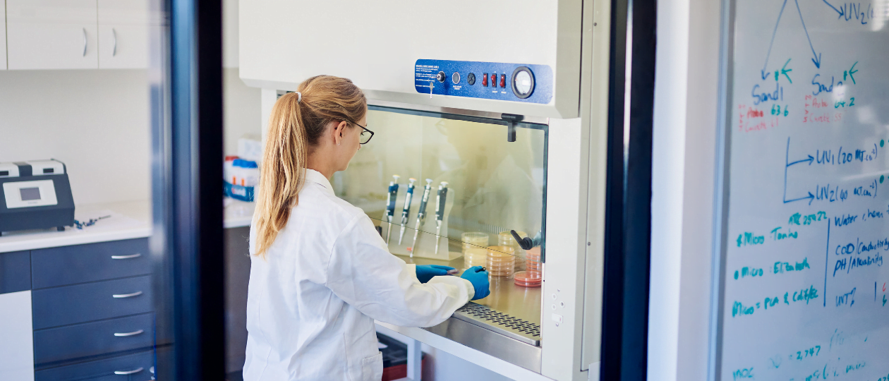Scientist sitting at safety cabinet examining samples