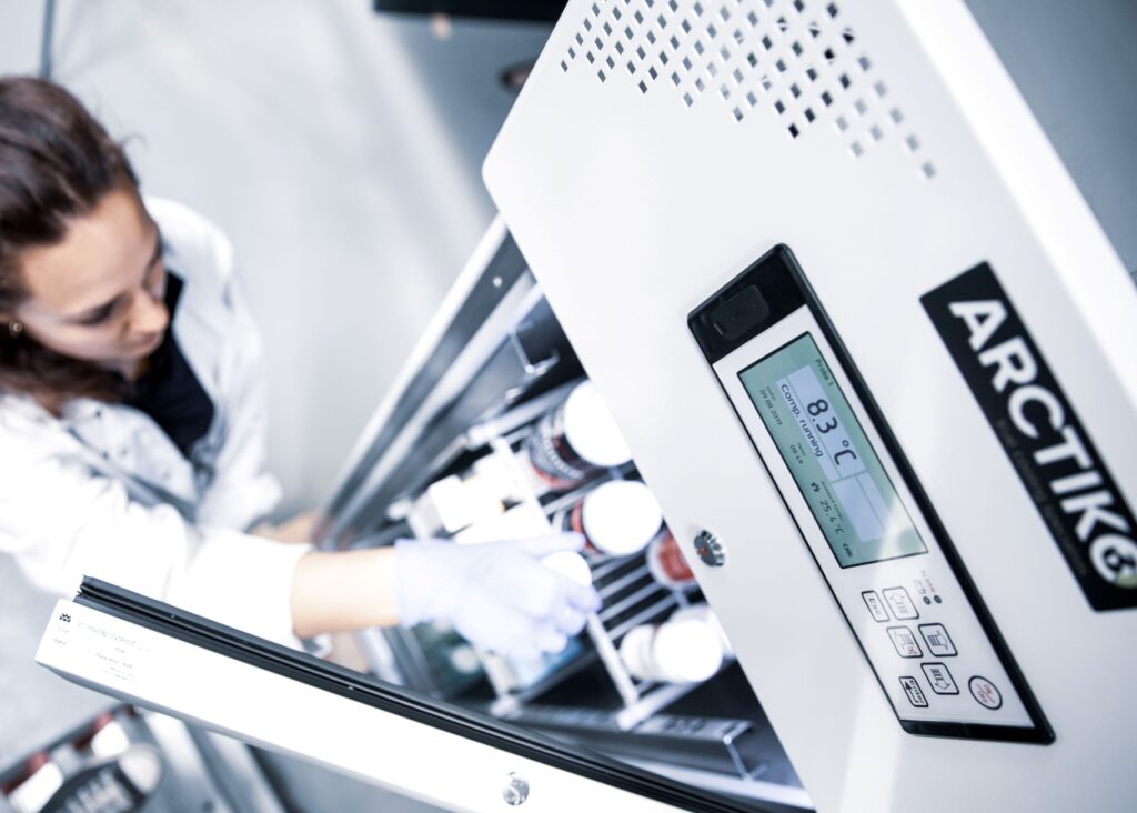Scientist placing sample into laboratory refrigerator